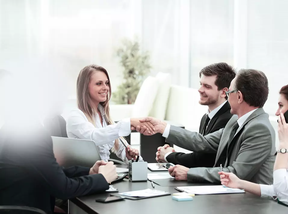 Business people shaking hands across a meeting table